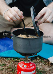 户外露营便携炉具煮面特写，红气罐与黑色锅具细节清晰