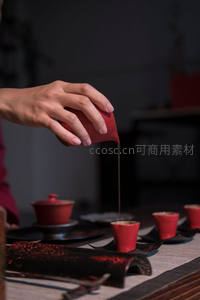 中式茶艺手部特写，红釉公道杯倾注茶汤于小盏
