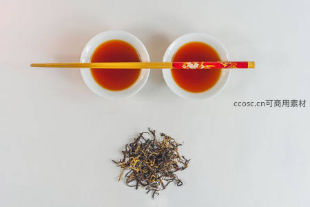 俯拍两杯红茶配红金纹筷子与散落干茶，极简中式茶点布局