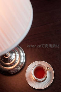 台灯暖光下瓷杯红茶静置深木桌，优雅复古氛围感十足
