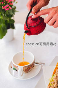 红釉镂空茶壶倾注琥珀茶汤，手部特写展现冲泡瞬间