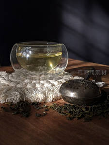 双层玻璃茶杯与金属茶滤：散茶与光影交织的静谧茶席