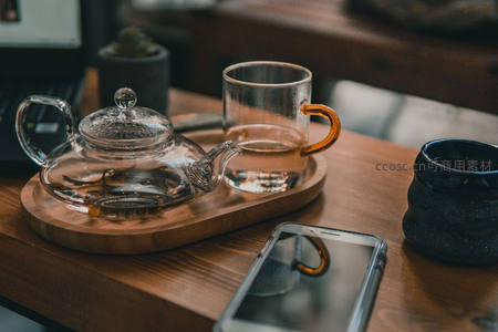 透明玻璃茶壶与手机共置木盘：现代办公茶歇场景