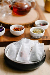 茶包静物组合：白色滤纸茶包置于深色陶碗中待用