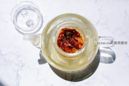 俯拍视角玻璃茶壶盛玫瑰花茶，盖子旁置，大理石台面光影交错