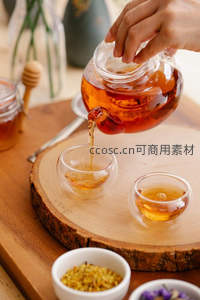 茶壶倾注茶汤入双杯，木纹托盘陈设干花与香料，构图平衡富有生活气息