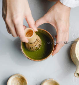 俯拍手执竹筅搅打抹茶，青翠茶汤泛起细腻泡沫