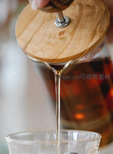 法压壶倾倒茶汤，晶莹液体如丝滑瀑布注入杯中