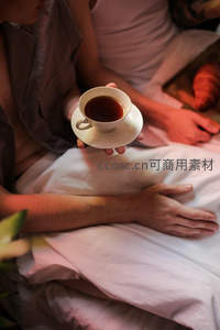 床上共享红茶时光，暖色调光影中两人亲密互动温馨惬意