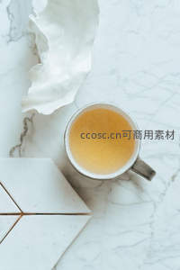 大理石台面俯拍茶杯，裂纹釉陶瓷盛金黄茶汤配几何石砖