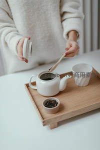 手作泡茶过程：白衣女子用木勺取茶叶入白瓷壶