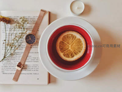 书页旁红釉茶杯与干橙片的静谧阅读时光