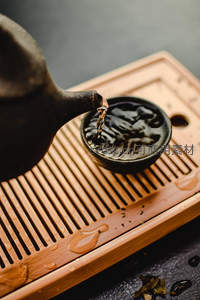 紫砂壶注茶特写：茶汤入黑釉小盏，竹制茶盘水珠晶莹