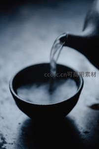 冷调光影中热水倾入黑陶小盏，水雾升腾瞬间凝固诗意