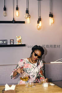 戴贝雷帽与墨镜的女子在复古灯饰下优雅冲泡花茶，氛围感十足