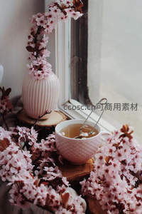 窗边樱花茶语：竖纹陶瓶插花与浮叶茶杯的诗意构图