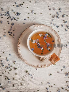 白瓷茶杯中漂浮紫花的清香花茶，散落花瓣点缀木质桌面