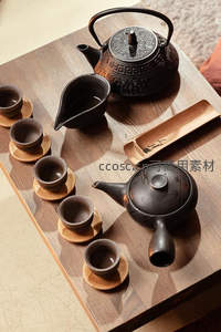 俯拍黑陶茶具组合：雕纹铁壶、竹制茶则与六只小盏陈列于木桌