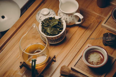 中式茶席俯拍：玻璃公道杯、干茶叶碗、白瓷茶壶与拉花茶汤，竹制茶盘雅致陈列