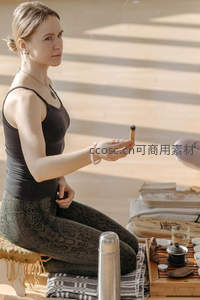 女子盘坐禅修手持艾条，阳光洒落茶席静谧氛围