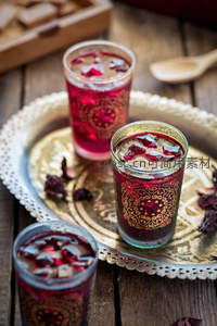 三杯玫瑰洛神花茶置于雕花铜盘，木桌背景古朴雅致