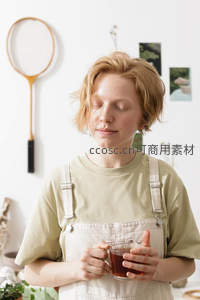 金发女子闭目品茶，简约家居环境中的宁静时刻