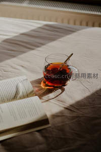 窗影斑驳下的玻璃茶杯与翻开的书本