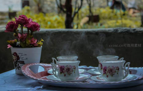 庭院石台上的花茶套装与盆栽玫瑰