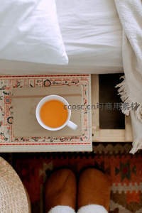 床边民族风小桌上的橙茶与毛绒拖鞋俯拍