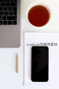 白色桌面上笔记本电脑、手机与红茶的极简工作台