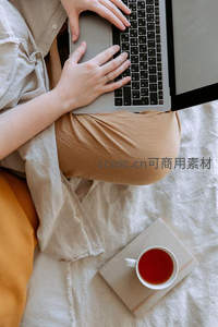 手部特写操作笔记本电脑，搭配茶杯与书本的宁静时刻