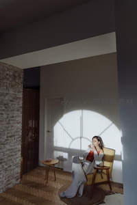 光影斑驳室内角落，女子裹毯啜饮咖啡静享独处