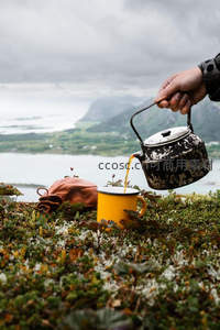 荒野苔原上旧铁壶 Pour 黄色搪瓷杯，远山云海映衬户外茶歇时光