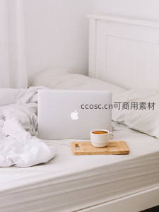 床头笔记本电脑旁一杯热咖啡，慵懒晨间工作场景