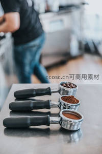 三款咖啡粉粗细对比：整豆、粗研磨、细研磨，置于金属手柄中展示