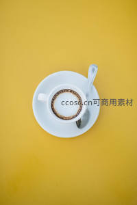 极简黄背景上白瓷咖啡杯与勺子构成清新构图