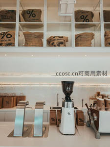 明亮现代咖啡店内部，白色磨豆机与品牌麻袋陈列，彰显极简工业风美学