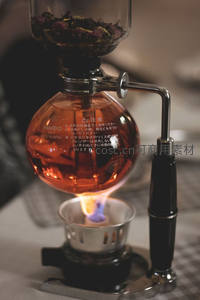 虹吸壶煮咖啡特写：火焰加热球形玻璃壶，内盛琥珀色咖啡液，日文警示标识清晰