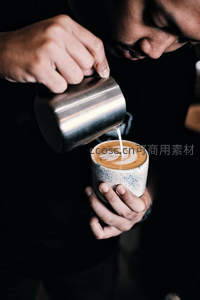 咖啡师专注拉花，奶泡注入形成精致叶形图案