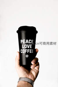 手持黑色‘PEACE LOVE COFFEE’星巴克杯，极简白背景下传递温暖理念