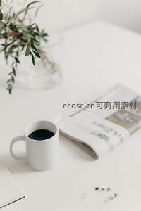 白色办公桌上的黑咖啡、绿植与报纸静物