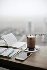 窗边木桌咖啡与笔记并置，城市朦胧远景映衬高效工作片刻