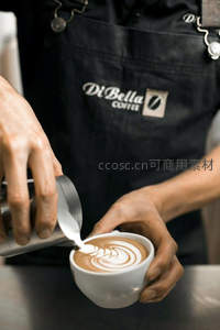 咖啡师专注制作拉花：奶泡旋涡在白瓷杯中绽放艺术之美
