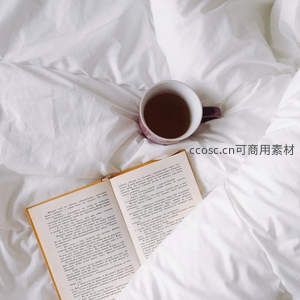 书香与热茶：白色床单上的开卷阅读与陶瓷杯静物