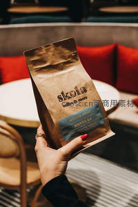 手握肯尼亚AA咖啡豆袋：精品咖啡品牌特写与质感呈现