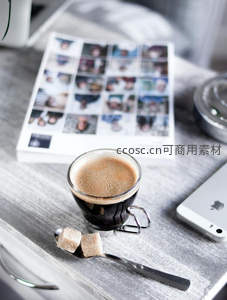 木质桌面上的意式浓缩咖啡与方糖，搭配照片集与手机