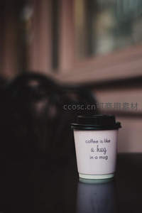 粉色纸杯咖啡特写，印有‘coffee is like a hug’温暖文案