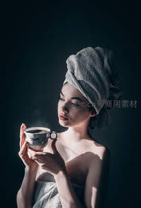 裹毛巾女子手持热咖啡，逆光剪影展现宁静晨间仪式感