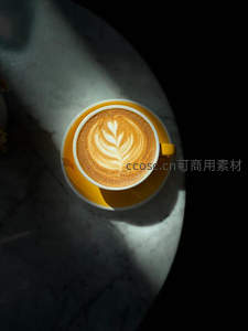黄杯拿铁拉花叶形图案，大理石台面光影交错