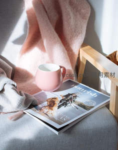 粉色咖啡杯置于杂志与毛毯上的慵懒午后